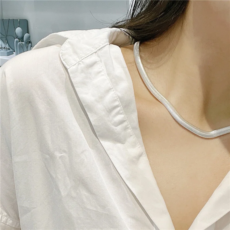 Side view of S925 sterling silver flat snake necklace worn with white shirt, minimalist collarbone styling