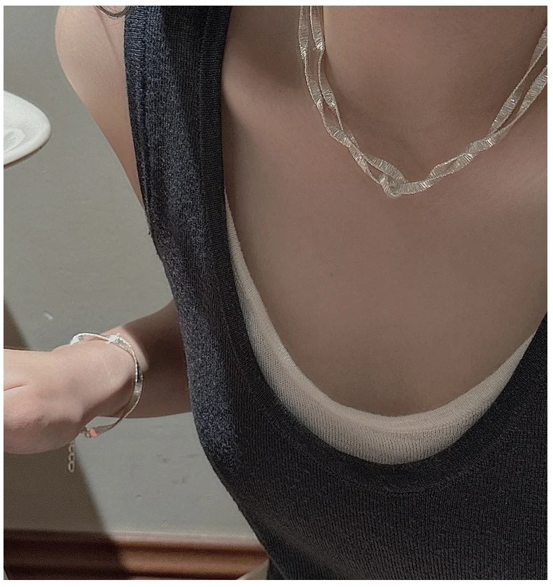 Layered S925 wavy ribbon silver necklace worn with matching silver bracelet, dark tank top outfit