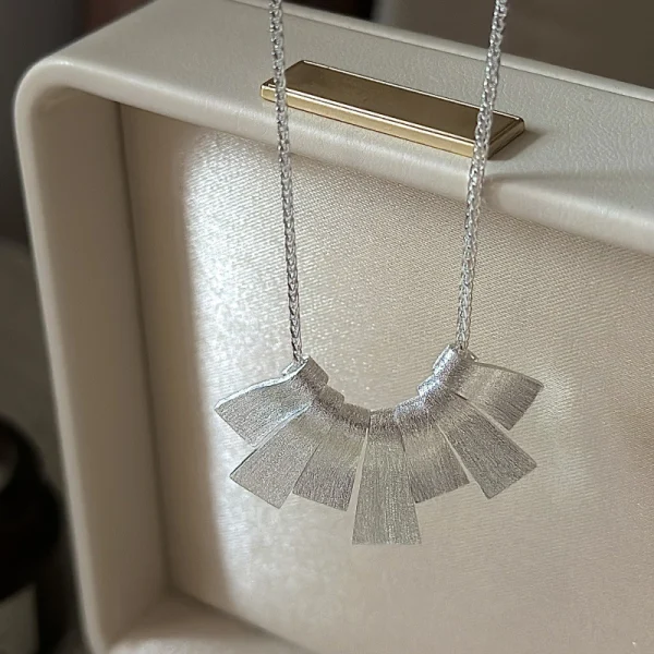 S925 sterling silver brushed fan pendant necklace displayed in cream leather jewelry box, artistic matte silver necklace for women