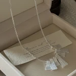 Flat lay of S925 silver fan pendant necklace in jewelry box with vintage greeting card, romantic gifting display