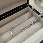 Close up of S hook clasp of S925 flat snake chain necklace inside lined black jewelry box