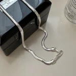 Full length S925 flat snake silver chain laid on black glossy jewelry box, flexible wavy snake chain