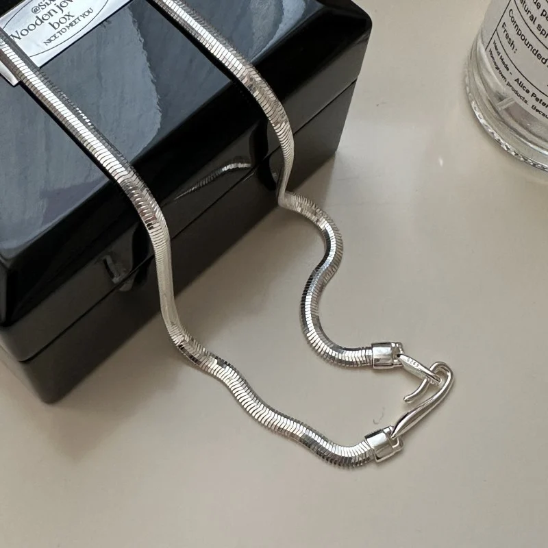 Full length S925 flat snake silver chain laid on black glossy jewelry box, flexible wavy snake chain