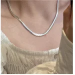 Close-up shot of S925 flat snake chain necklace resting on collarbone, white square neck top