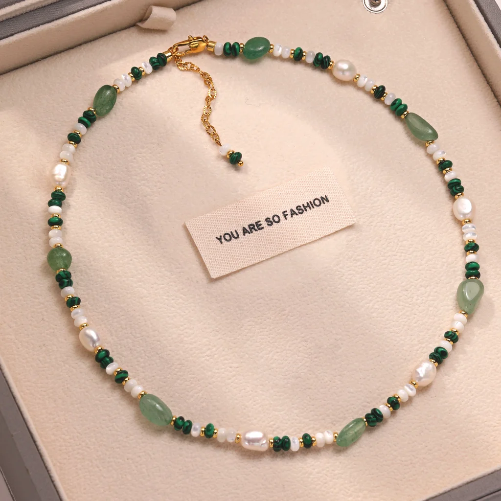 Product advertisement for natural freshwater pearl and crystal beaded necklace and bracelet set with Flowing Light Radiant Color theme, featuring baroque pearls, malachite, aventurine, and 18K gold-plated beads on gradient green background by MAISON ELARA & CO