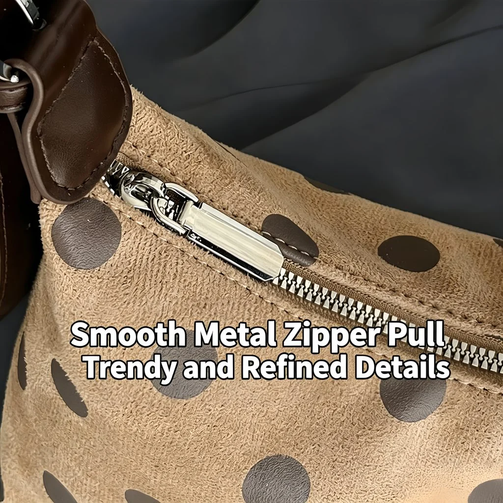 Close-up of smooth metal zipper pull on polka dot suede hobo bag, hardware detail shot