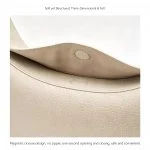 Side profile of cream genuine leather crescent hobo bag showing curved silhouette and tapering ends with gold tone hardware attachment and smooth matte leather surface