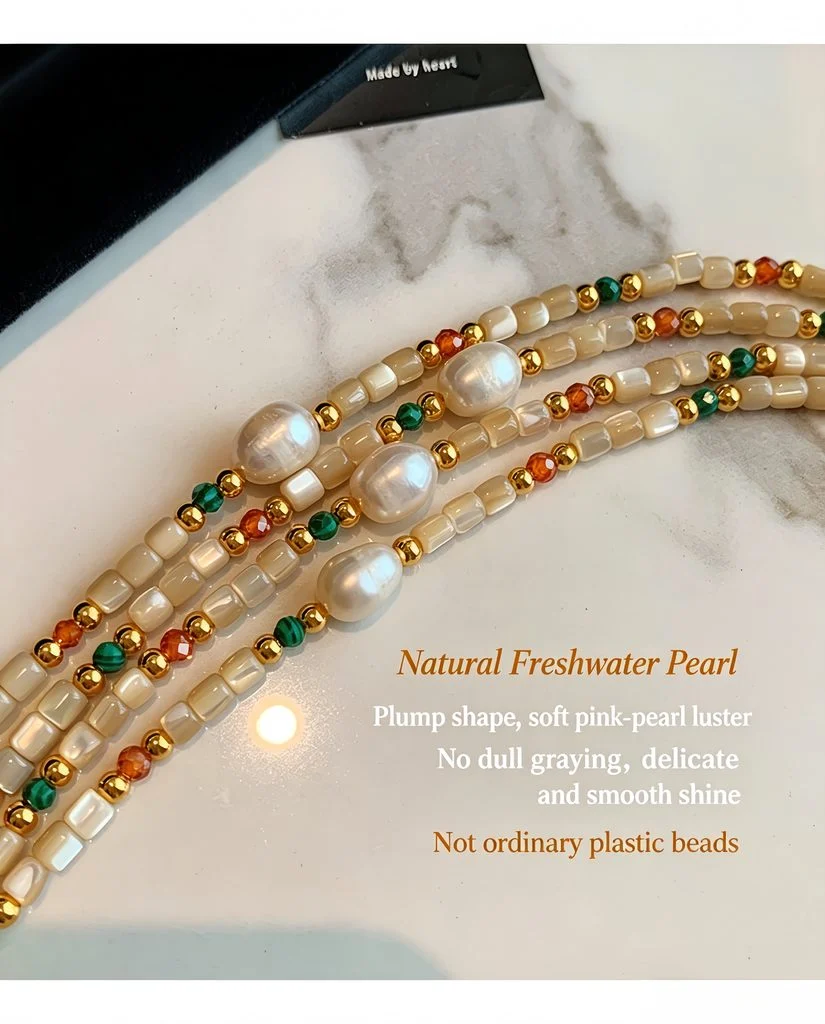 Natural stone and shell beaded necklace laid flat on a marble surface, showing the full strand and gold tone extender chain