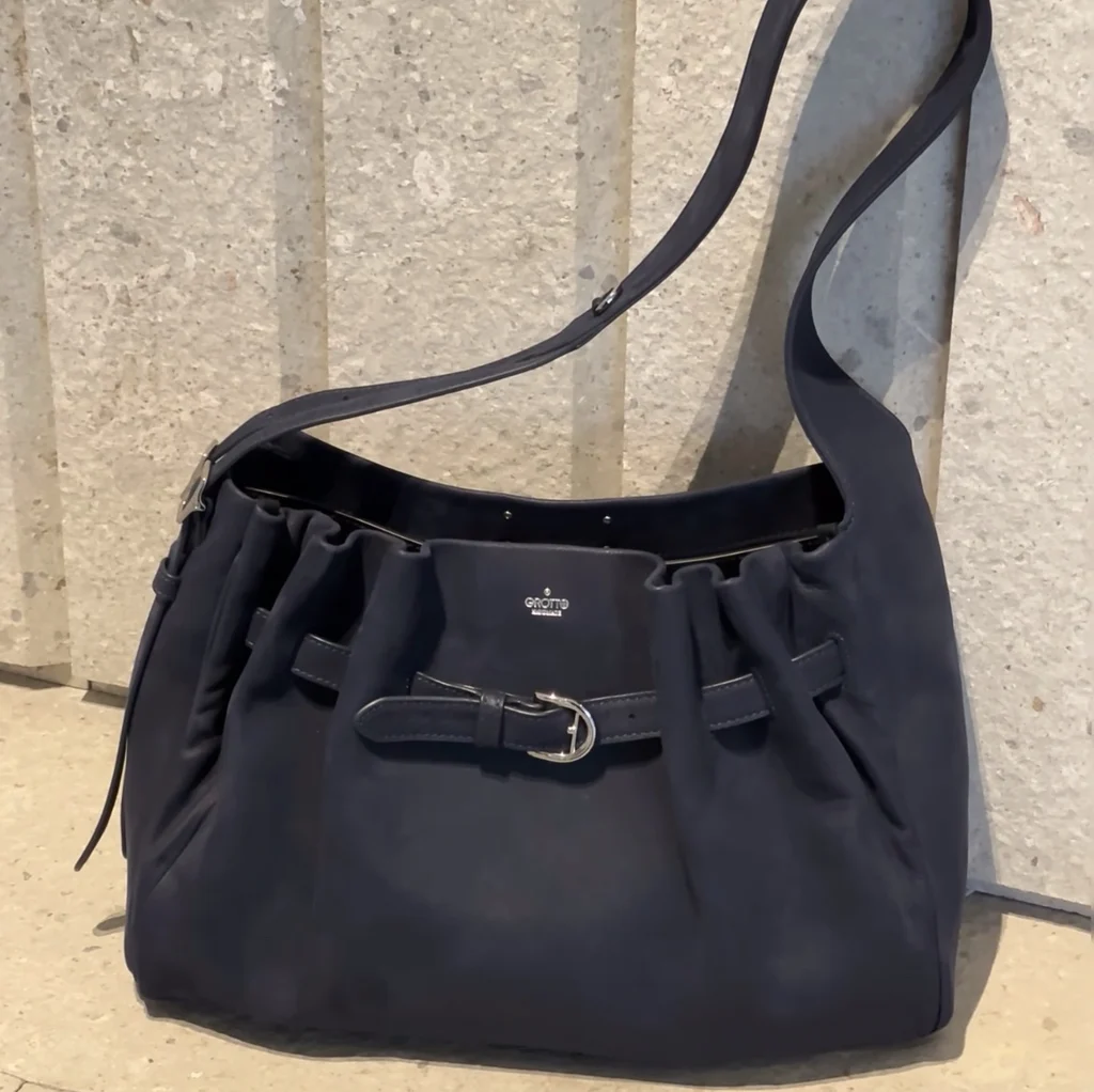 Top-down view of genuine leather hobo bag interior showing three-layer compartment with snap button and zipper pockets