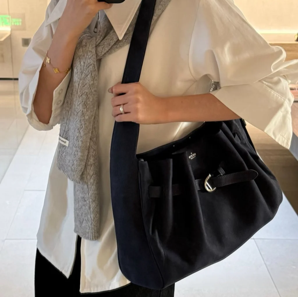 Woman carrying navy genuine leather hobo tote bag over shoulder, casual office daily outfit