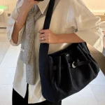 Woman carrying navy genuine leather hobo tote bag over shoulder, casual office daily outfit