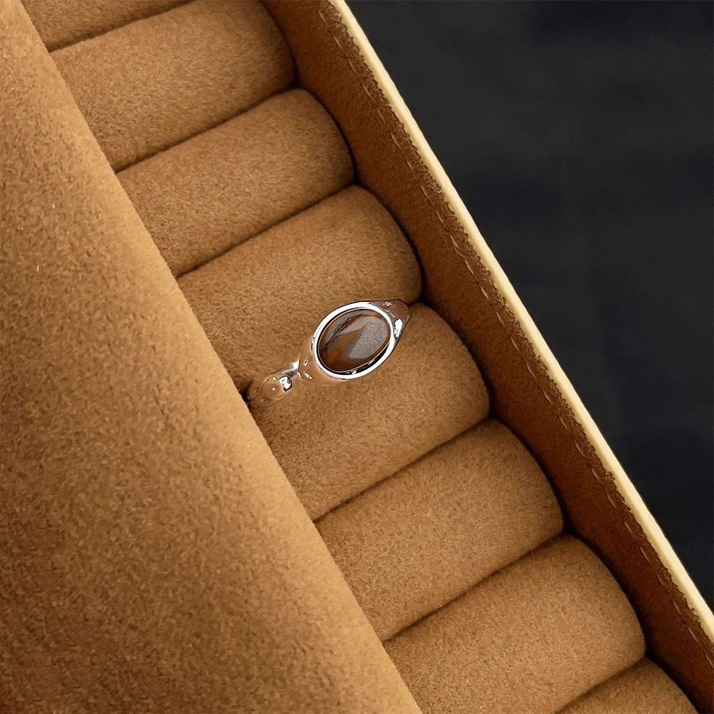 Vintage gold ring with red gemstone worn on finger with knit sweater, atmospheric jewelry photography