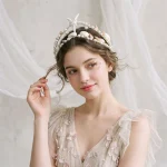 Bride in tulle dress wearing starfish shell pearl crown in soft indoor backdrop